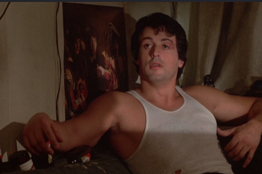 Rocky sitting in his cramped, dark apartment